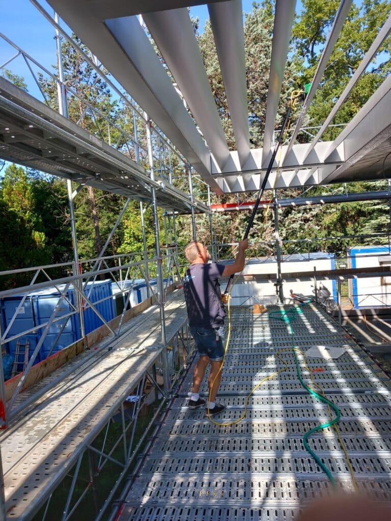 Technicien réalisant un nettoyage en hauteur sur une structure métallique, intervention professionnelle pour l'entretien certifié à Genève par Vitre et Clair, entreprise spécialisée.