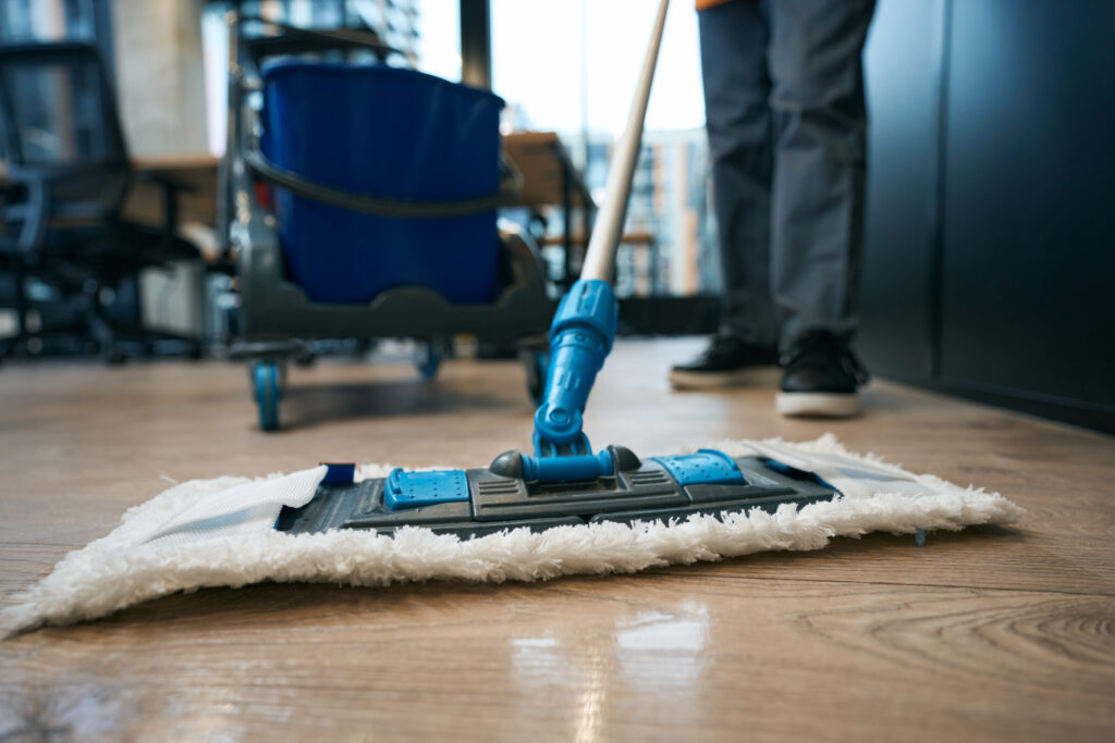 Ménage professionnel avec balai microfibre sur sol en bois, prestation de nettoyage disponible à Genève par Vitre et Clair