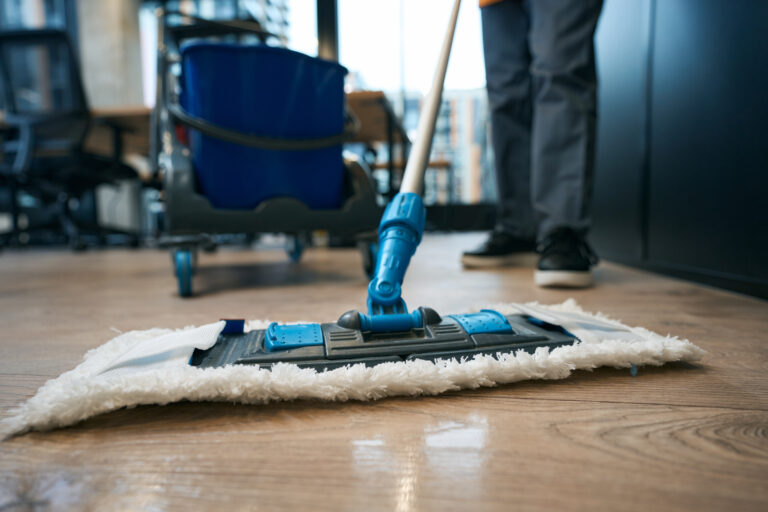 Ménage professionnel avec balai microfibre sur sol en bois, prestation de nettoyage disponible à Genève par Vitre et Clair